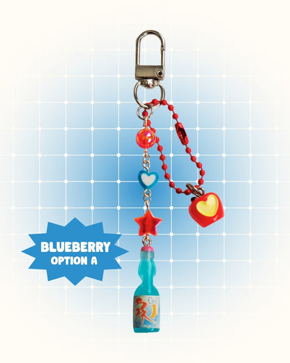 Colorful keychain with blueberry flavor soda on a light blue grid background