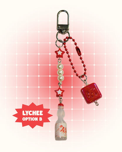 Keychain with red dice charm and Lychee flavored soda on a red grid background