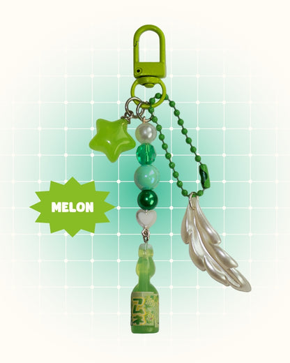 Green melon soda keychain with decorative elements on a light green background